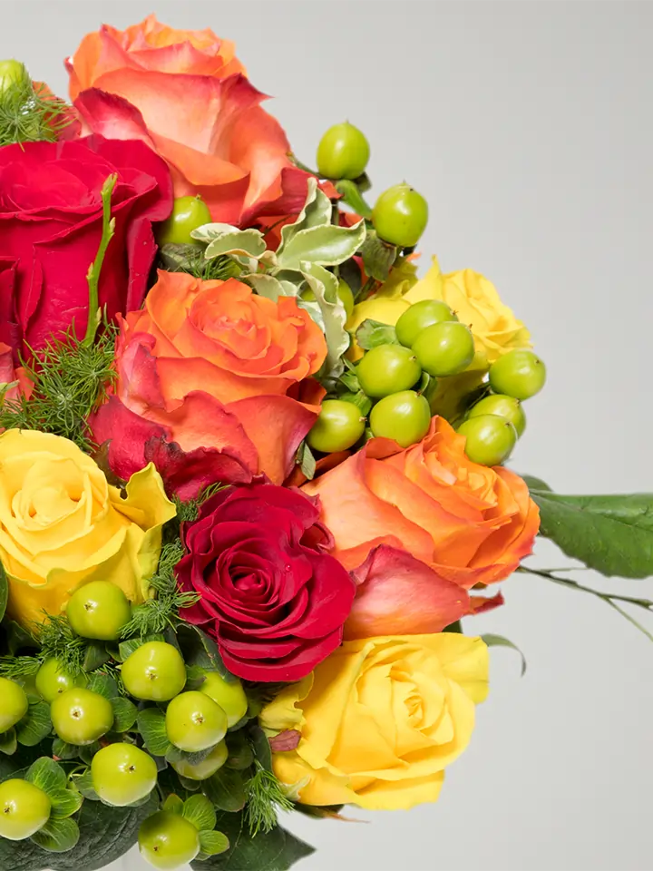 Bouquet di rose aranco rosse giallo e bacche verdi macro